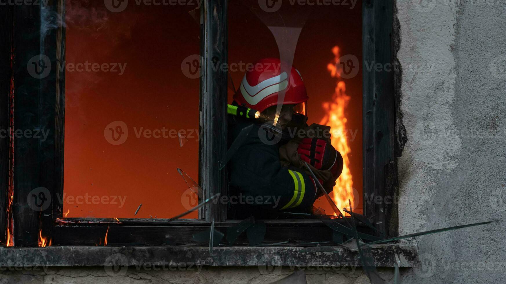 Firefighter hero carrying baby girl out from burning building area from fire incident. Rescue people from dangerous place photo