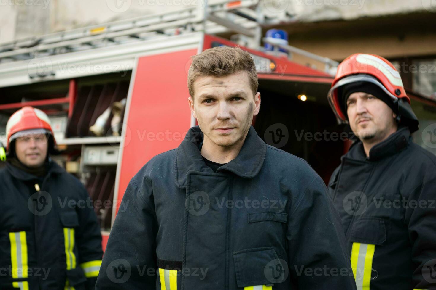 Group of fire fighters standing confident after a well done rescue operation. Firemen ready for emergency service. photo