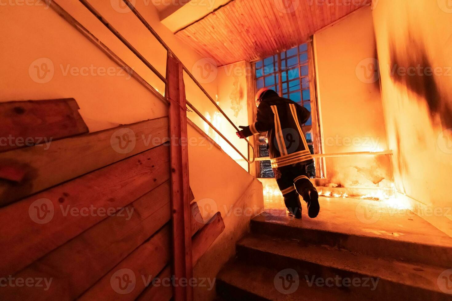 Brave Fireman going upstairs to save and rescue people in a Burning Building. Open fire and flame. photo