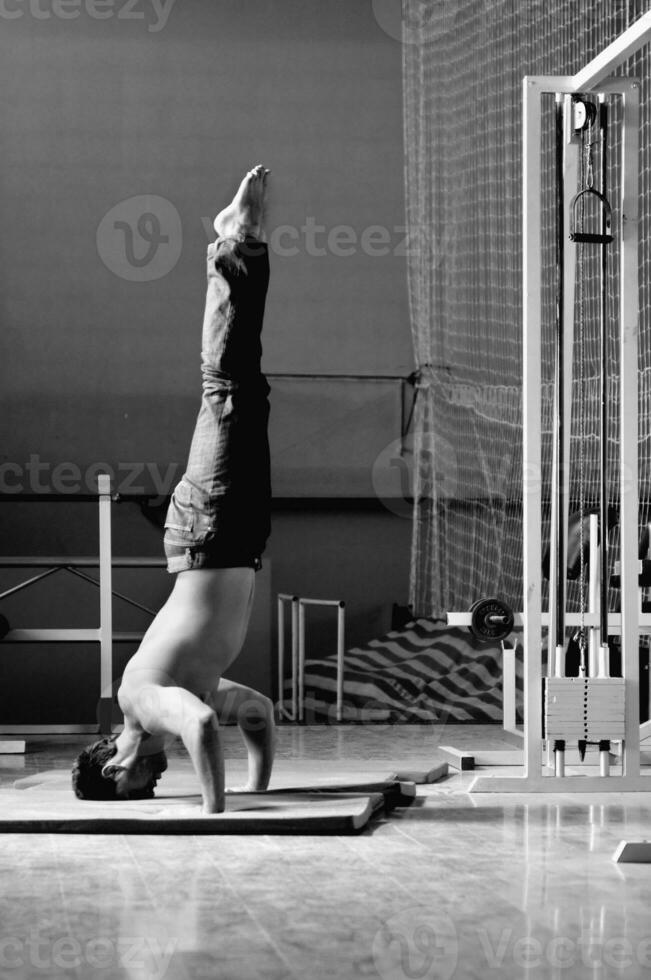 Young man performing  handstand in fitness studio photo