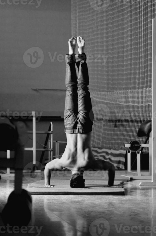 Young man performing  handstand in fitness studio photo