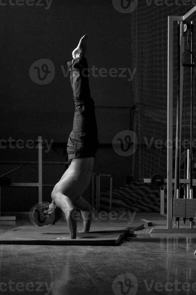 young man performing handstand in fitness studio photo