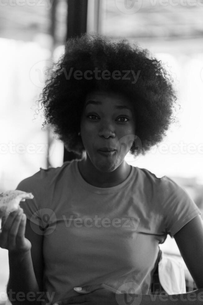 mujer con peinado afro comiendo una sabrosa rebanada de pizza foto