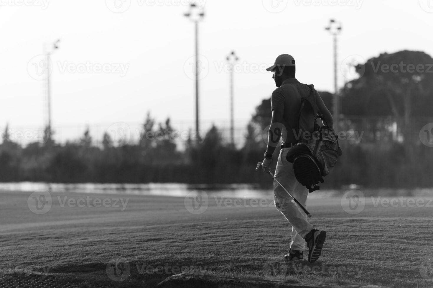 golfista caminando y llevando una bolsa de golf al hermoso atardecer foto