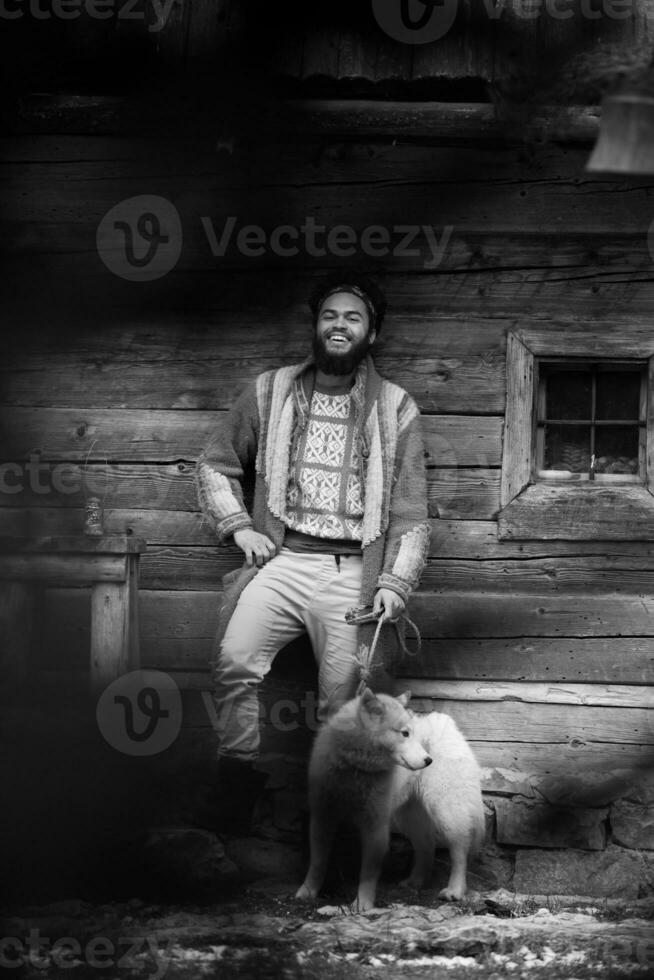 hipster con perro frente a casa de madera foto