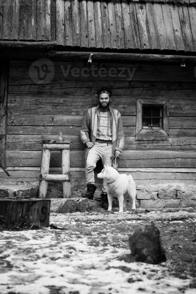 hipster with dog in front of wooden house photo