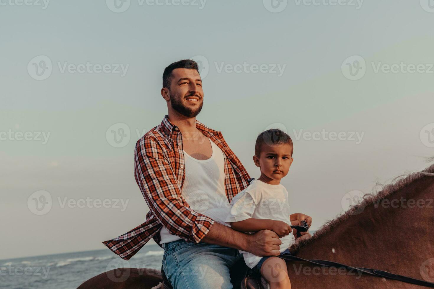 Father and son enjoy riding horses together by the sea. Selective focus photo