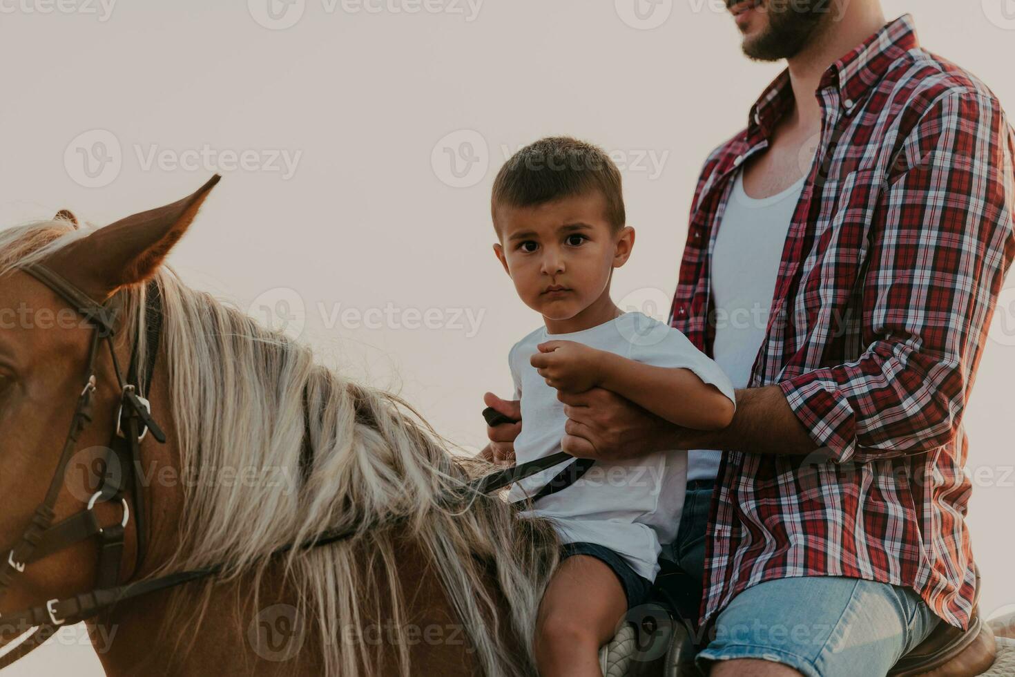 Father and son enjoy riding horses together by the sea. Selective focus photo