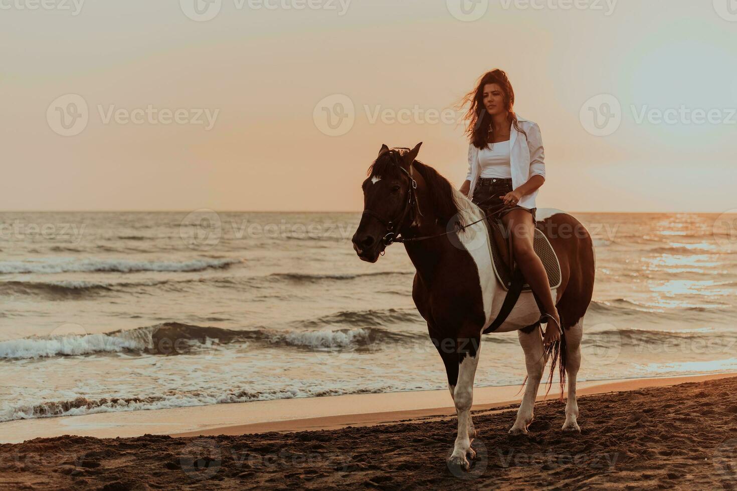 mujer vestida de verano disfruta montando a caballo en una hermosa playa de arena al atardecer. enfoque selectivo foto