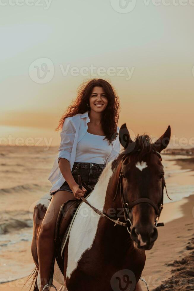 Woman in summer clothes enjoys riding a horse on a beautiful sandy beach at sunset. Selective focus photo