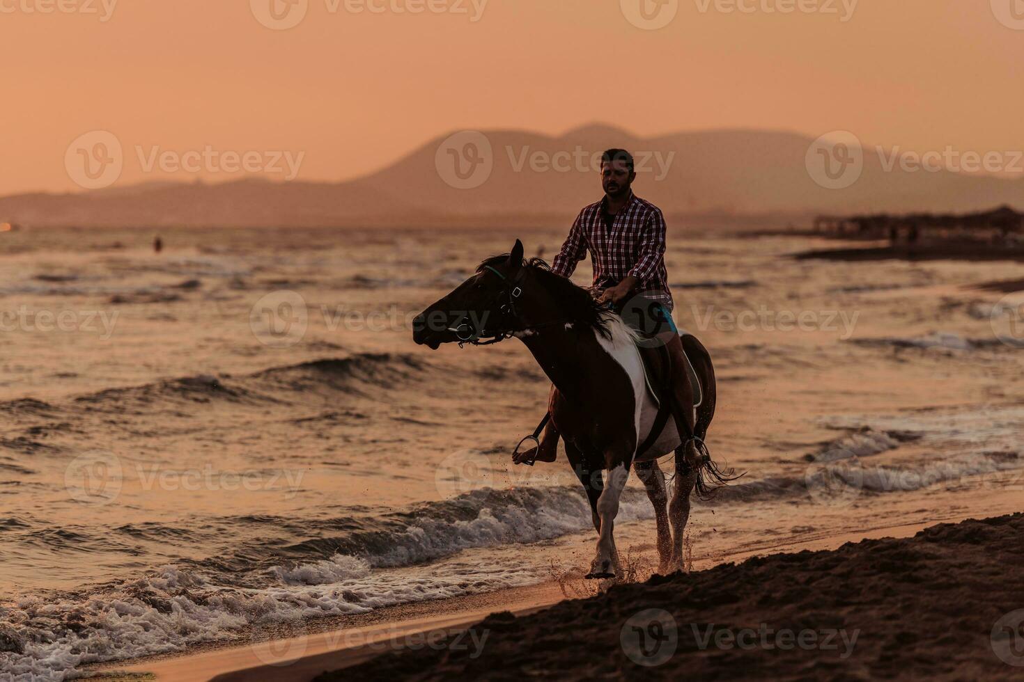 un hombre moderno con ropa de verano disfruta montando a caballo en una hermosa playa de arena al atardecer. enfoque selectivo foto