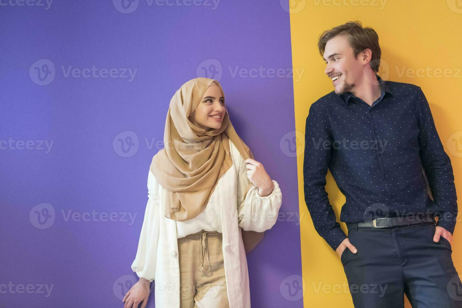 Portrait of a young Muslim couple woman in fashionable dress with hijab isolated on a colorful background representing modern Islam fashion and Ramadan Kareem concept photo