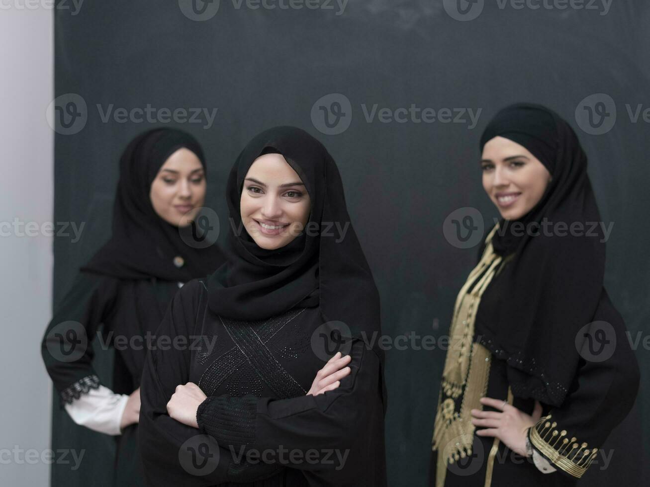 Group portrait of beautiful Muslim women in a fashionable dress with hijab isolated on black background photo