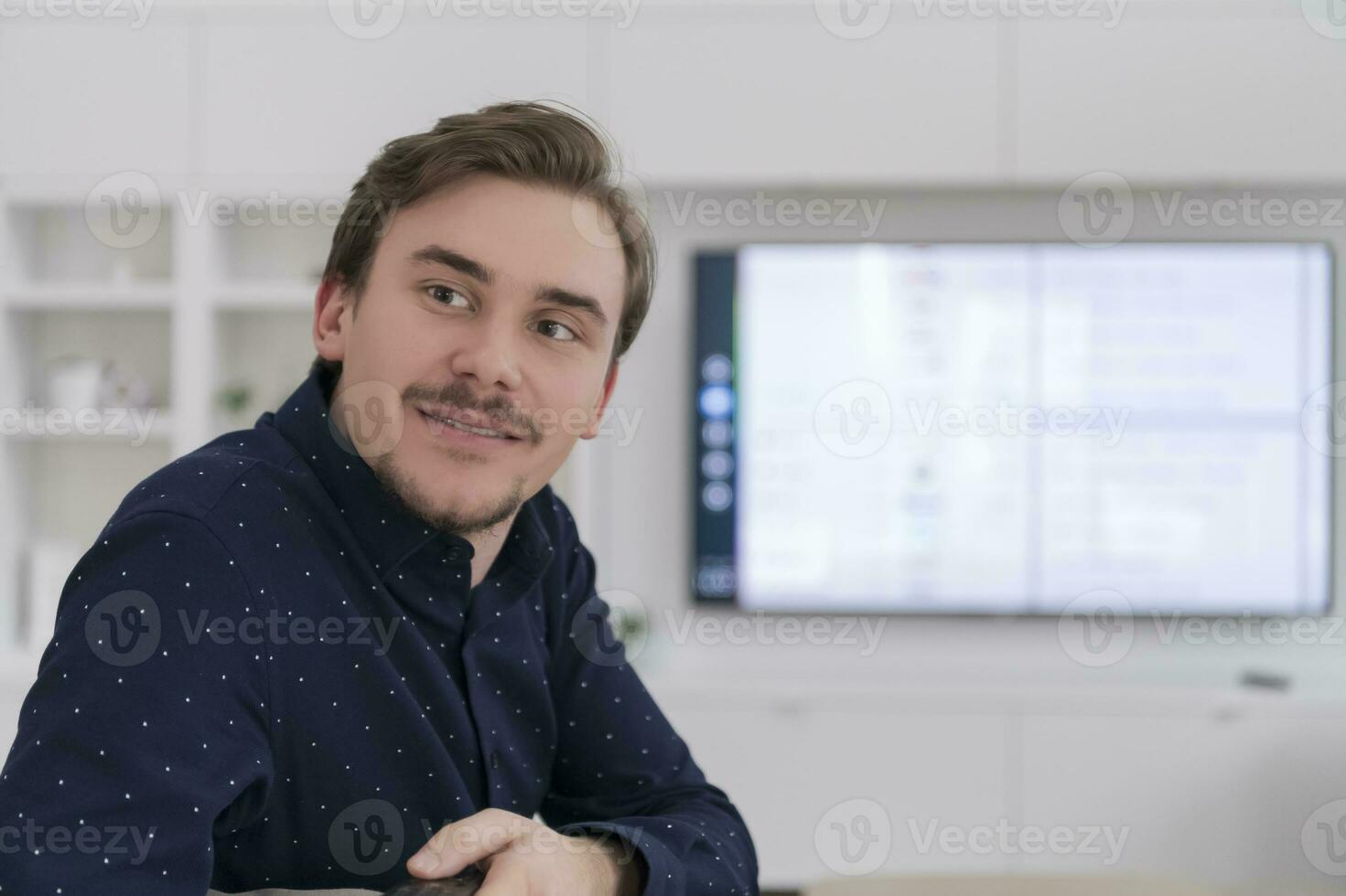 contento joven hombre disfrutando gratis hora sentado en el sofá mientras acecho televisión en grande moderno vivo habitación a hogar foto