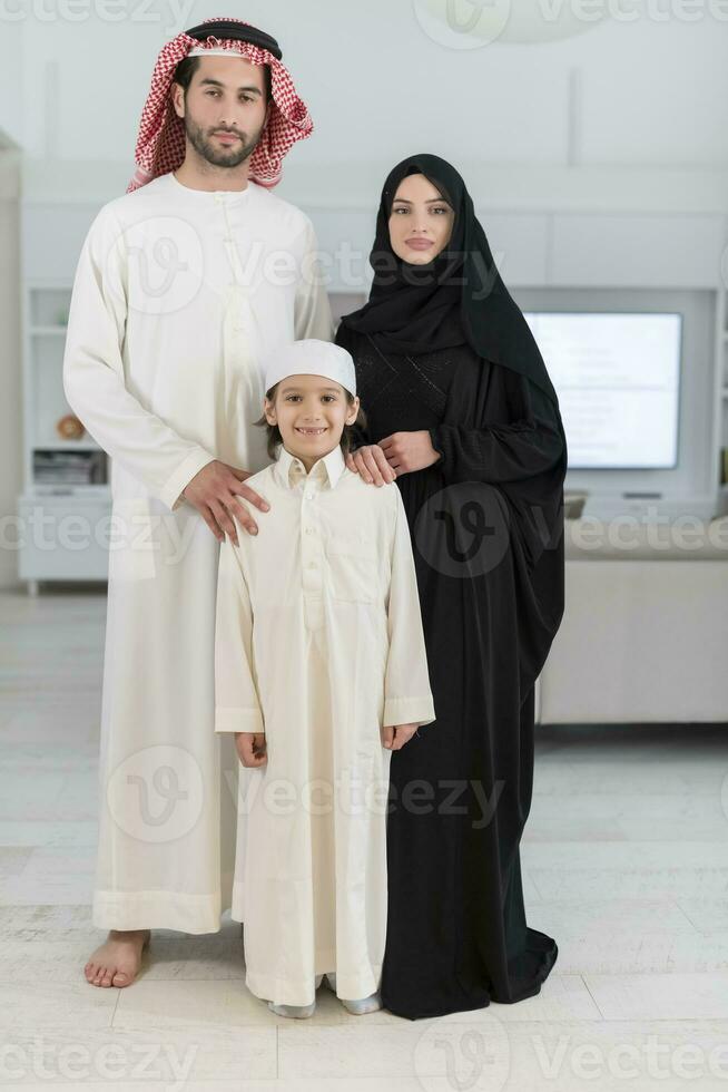 Portrait of a young happy Arabian Muslim family couple with a son in traditional clothes spending time together photo