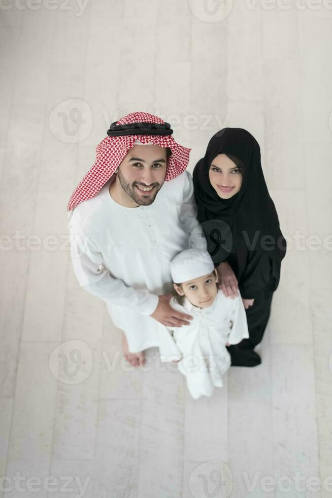 Portrait of a young happy Arabian Muslim family couple with a son in traditional clothes spending time together photo