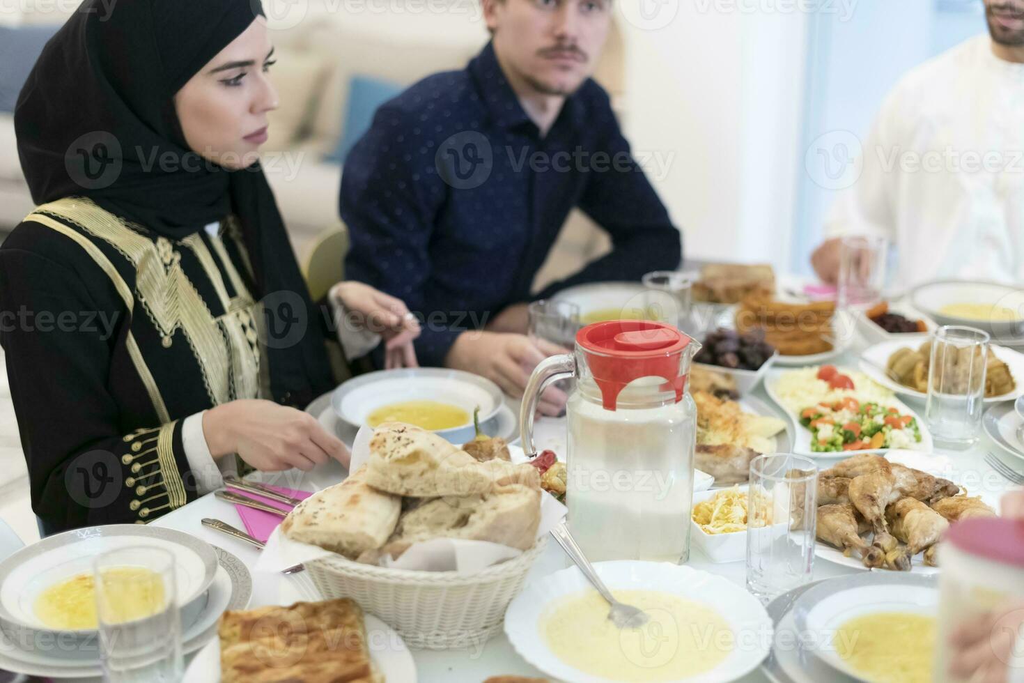 Eid Mubarak Muslim family having Iftar dinner drinking water to break feast. Eating traditional food during Ramadan feasting month at home. The Islamic Halal Eating and Drinking at modern western Isla photo