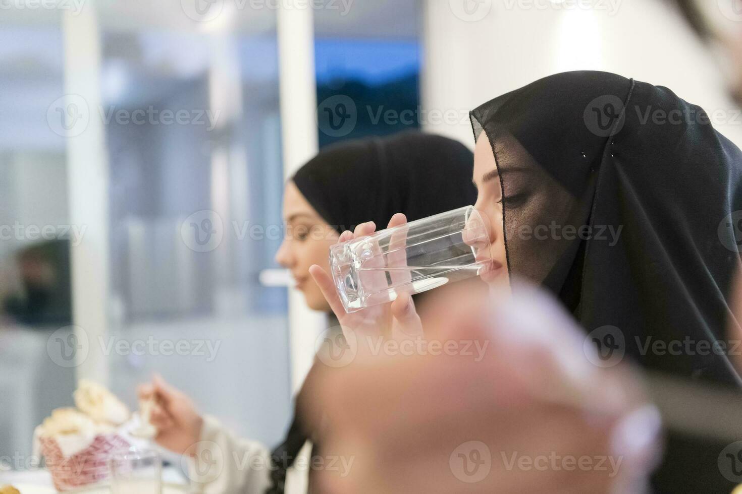 Eid Mubarak Muslim family having Iftar dinner drinking water to break feast. Eating traditional food during Ramadan feasting month at home. The Islamic Halal Eating and Drinking at modern western Isla photo