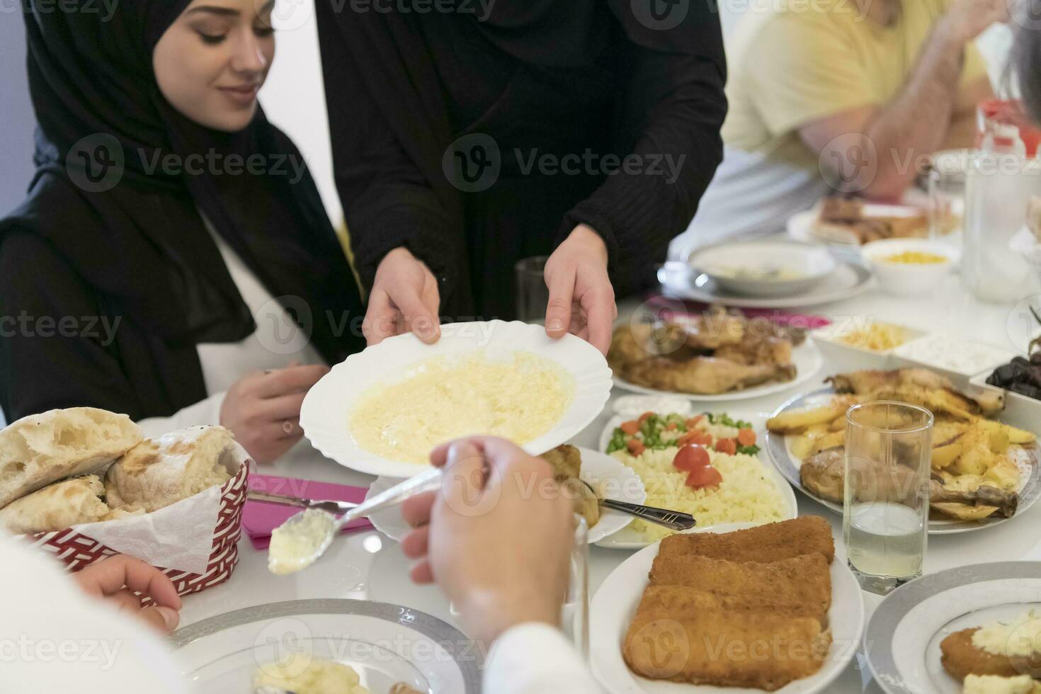 eid Mubarak musulmán familia teniendo iftar cena Bebiendo agua a descanso banquete. comiendo tradicional comida durante Ramadán banquete mes a hogar. el islámico halal comiendo y Bebiendo a moderno occidental isla foto