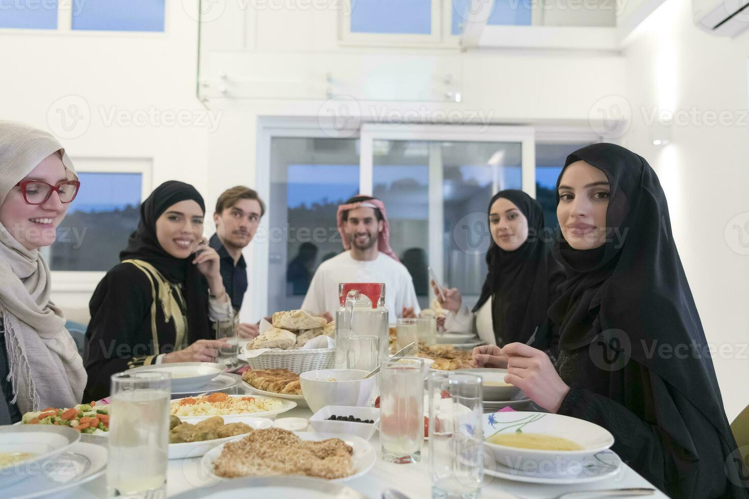 Eid Mubarak Muslim family having Iftar dinner drinking water to break feast. Eating traditional food during Ramadan feasting month at home. The Islamic Halal Eating and Drinking at modern western Isla photo