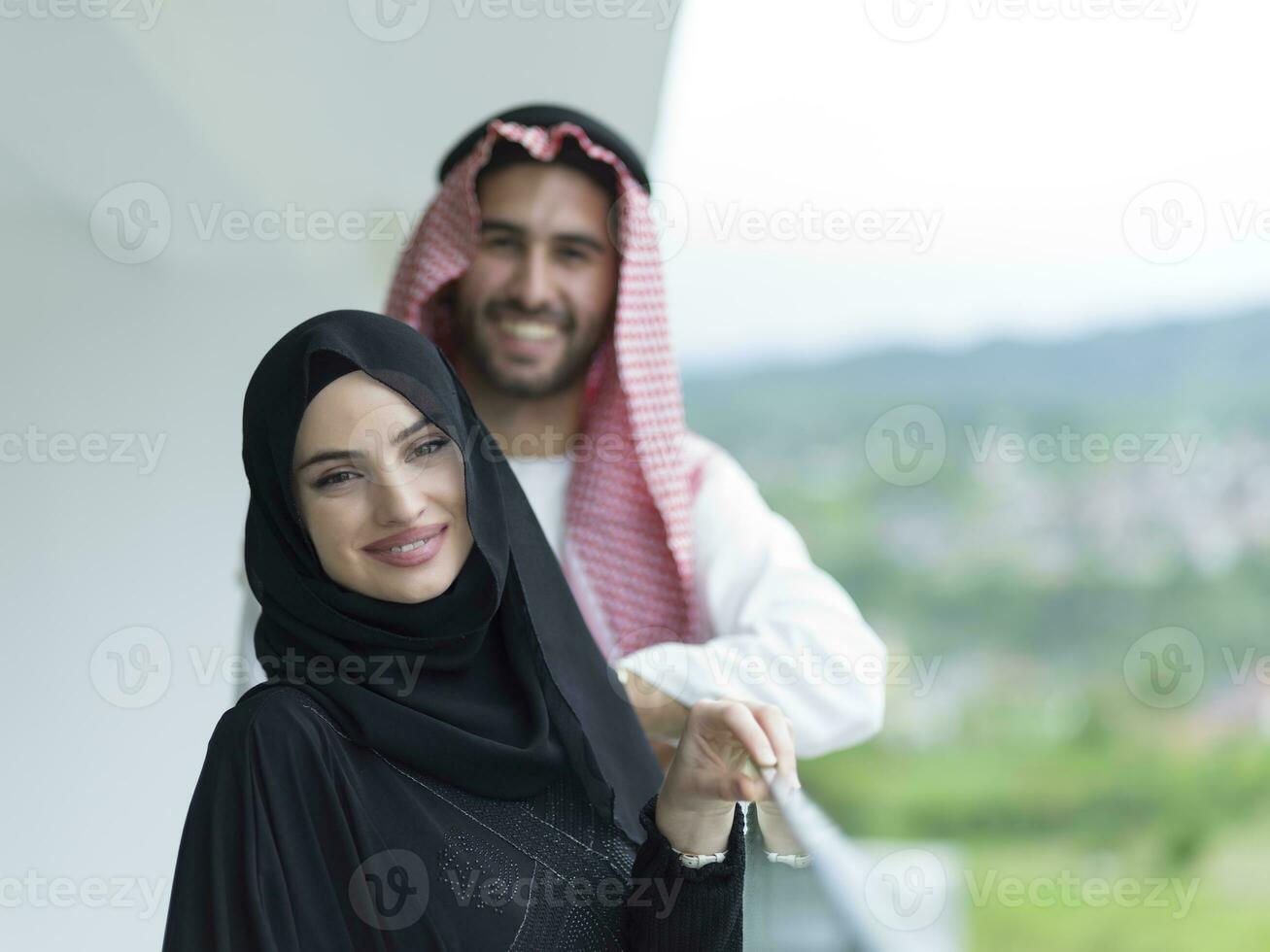 Portrait of a young Arabian Muslim couple in traditional clothes standing on a balcony representing modern Islam fashion and Ramadan Kareem concept photo