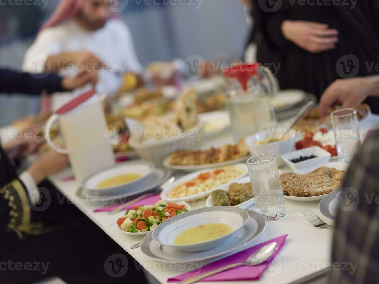 Eid Mubarak Muslim family having Iftar dinner drinking water to break feast. Eating traditional food during Ramadan feasting month at home. The Islamic Halal Eating and Drinking at modern western Isla photo