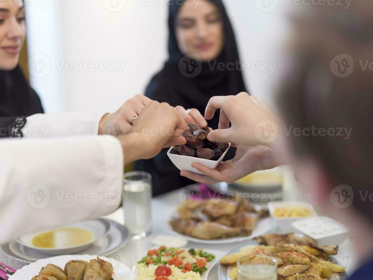 moderno multiétnico musulmán familia compartiendo un cuenco de fechas mientras disfrutando iftar cena juntos durante un Ramadán banquete a hogar foto