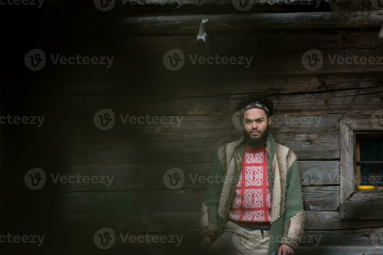 portrait of young hipster in front of wooden house photo