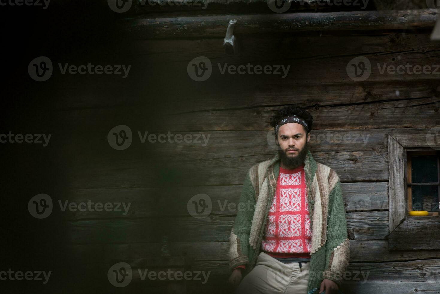 portrait of young hipster in front of wooden house photo