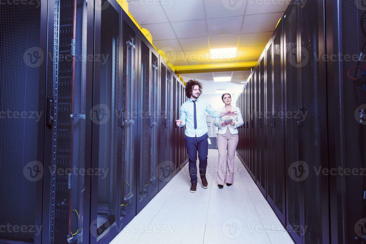 engineer showing working data center server room to female chief photo