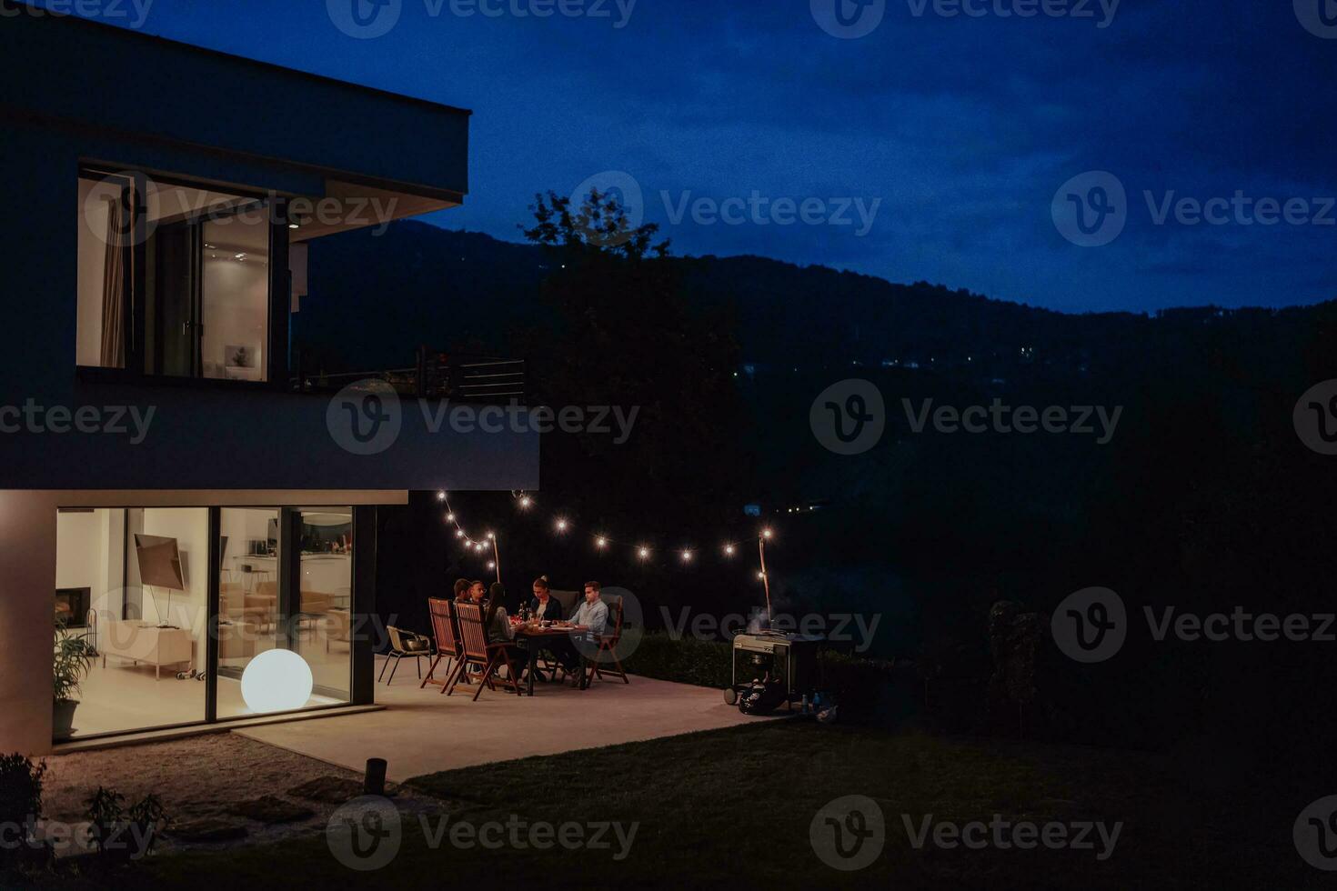 A group of young diverse people having dinner on the terrace of a modern house in the evening. Fun for friends and family. Celebration of holidays, weddings with barbecue. photo