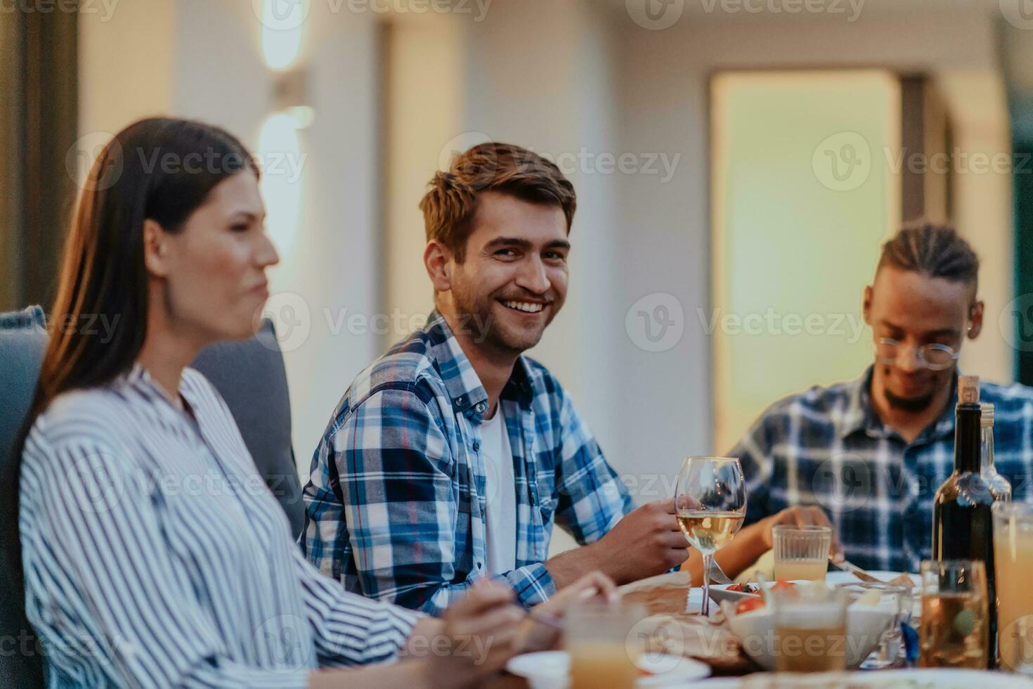 A group of young diverse people having dinner on the terrace of a modern house in the evening. Fun for friends and family. Celebration of holidays, weddings with barbecue. photo