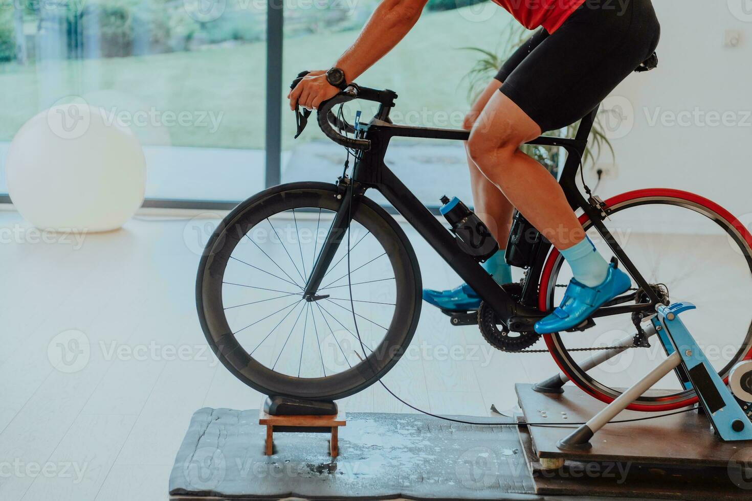 A man riding a triathlon bike on a machine simulation in a modern living room. Training during pandemic conditions. photo