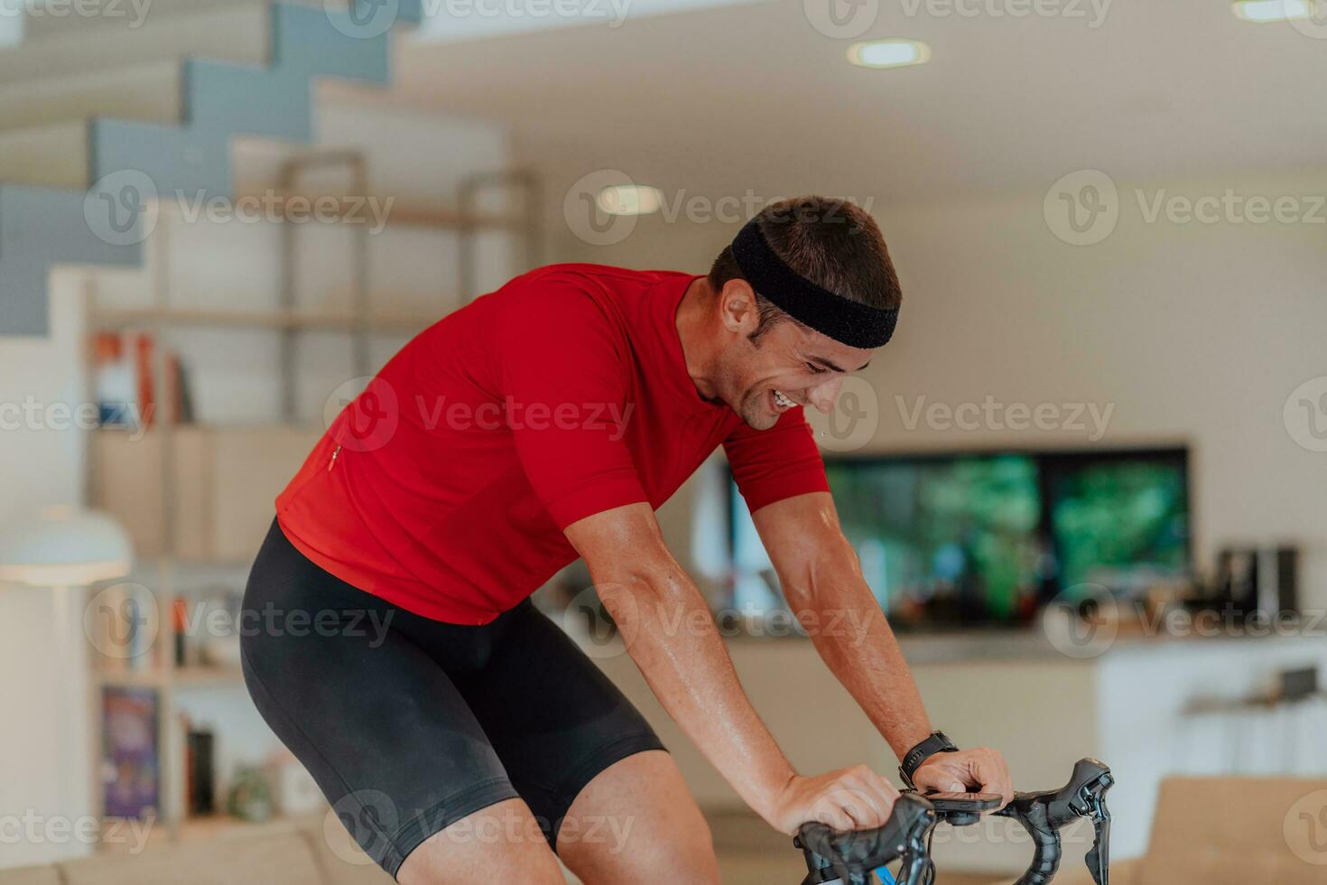 A man riding a triathlon bike on a machine simulation in a modern living room. Training during pandemic conditions. photo