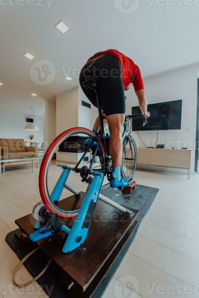 A man riding a triathlon bike on a machine simulation in a modern living room. Training during pandemic conditions. photo