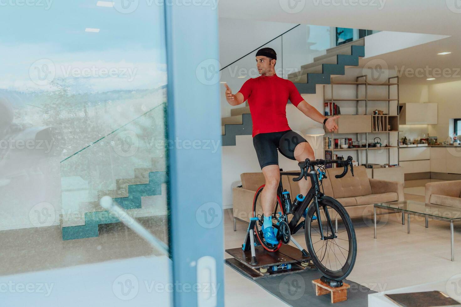 A man riding a triathlon bike on a machine simulation in a modern living room. Training during pandemic conditions. photo