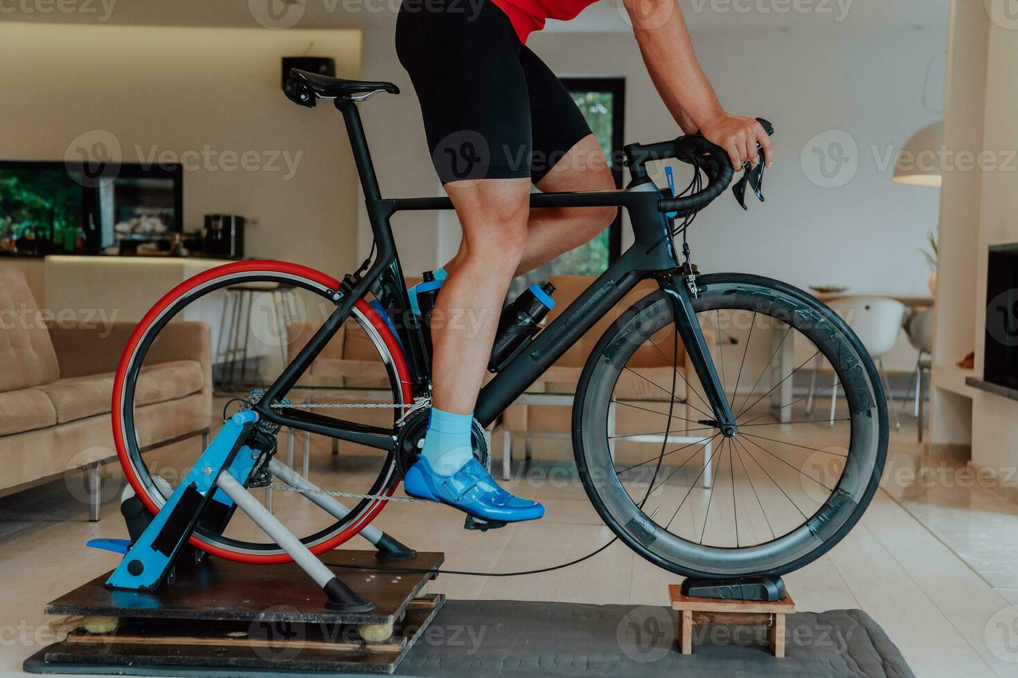 A man riding a triathlon bike on a machine simulation in a modern living room. Training during pandemic conditions. photo