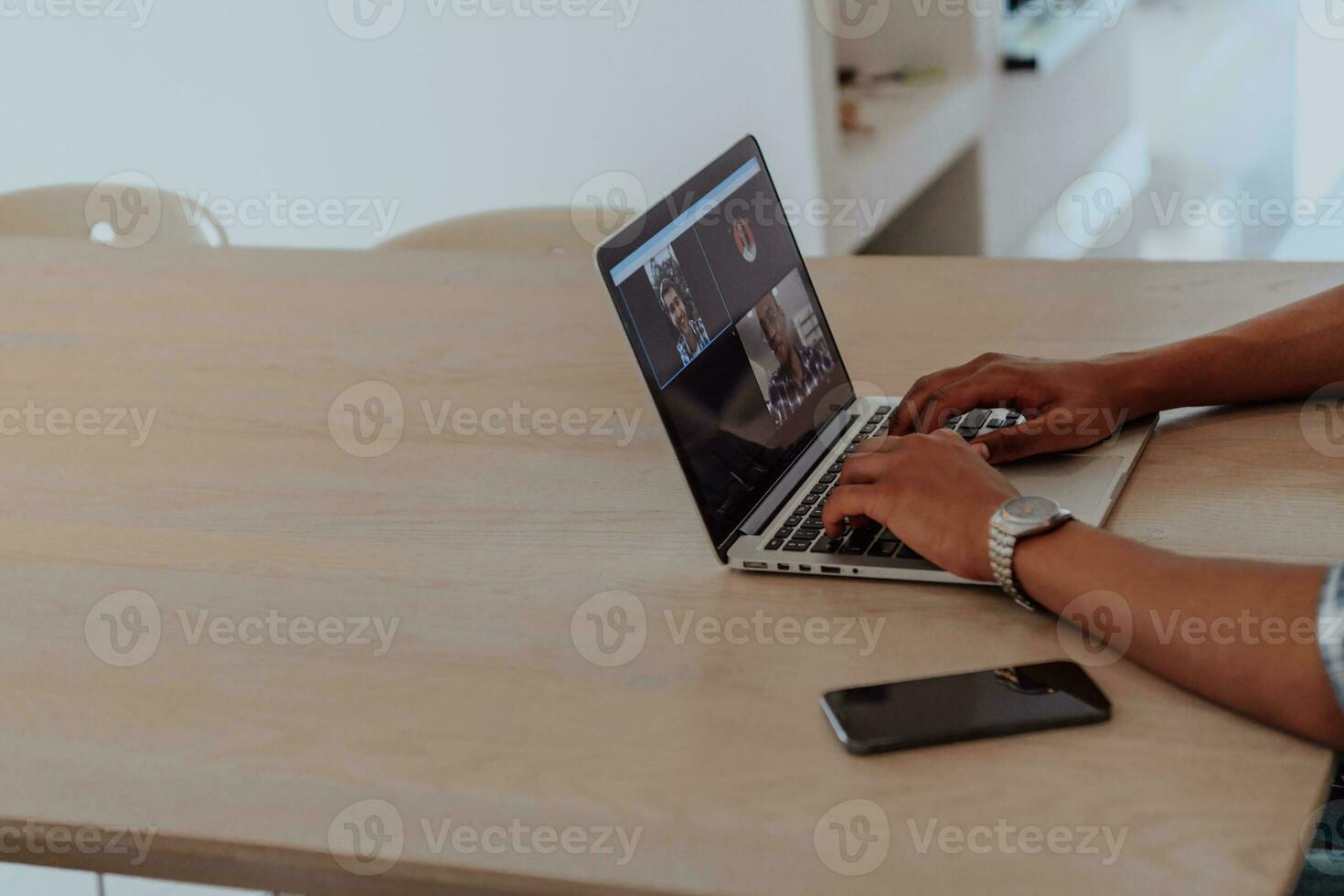 African American man in glasses sitting at a table in a modern living room, using a laptop for business video chat, conversation with friends and entertainment photo