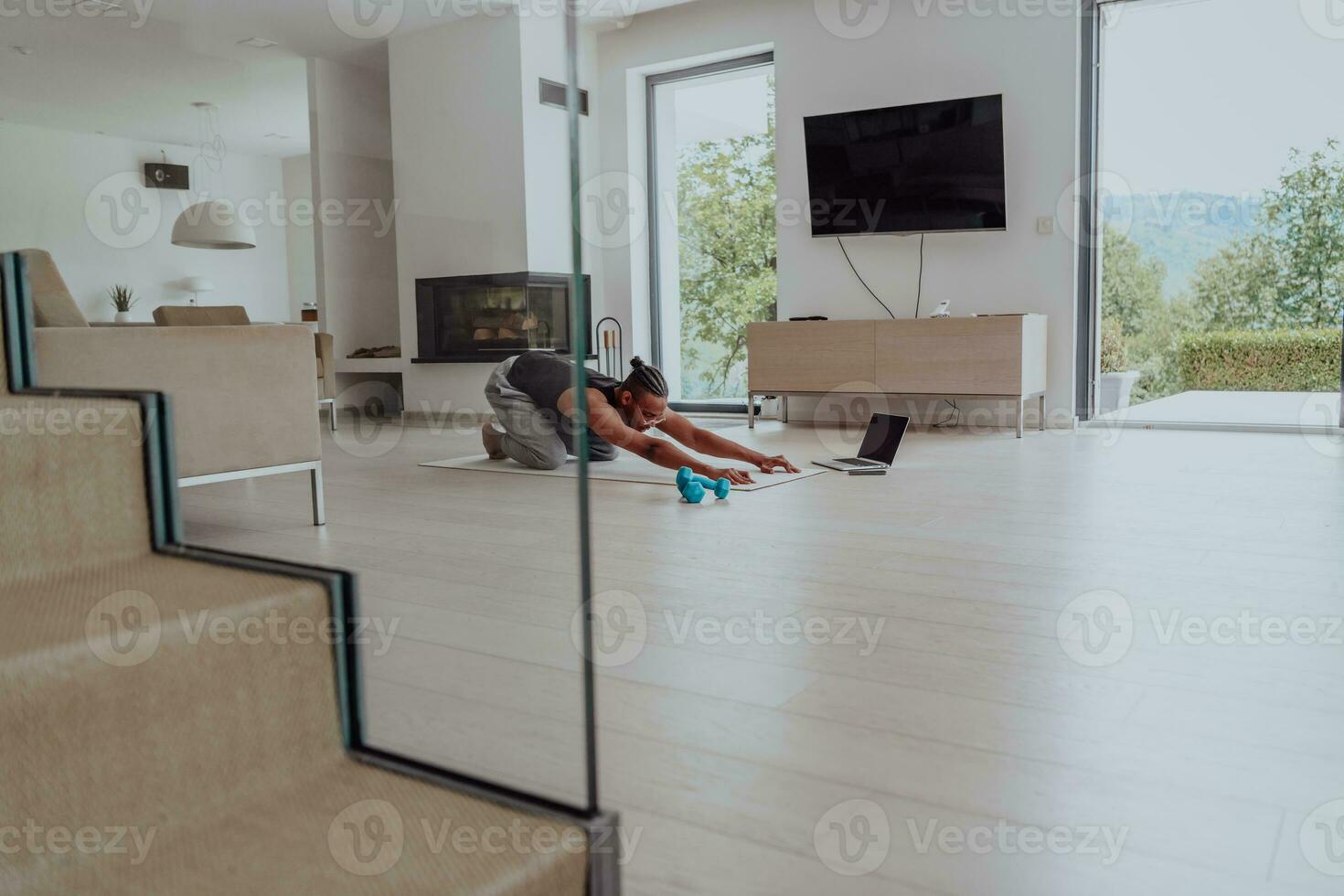 Training At Home. Sporty man doing training while watching online tutorial on laptop, exercising in living room, free space photo