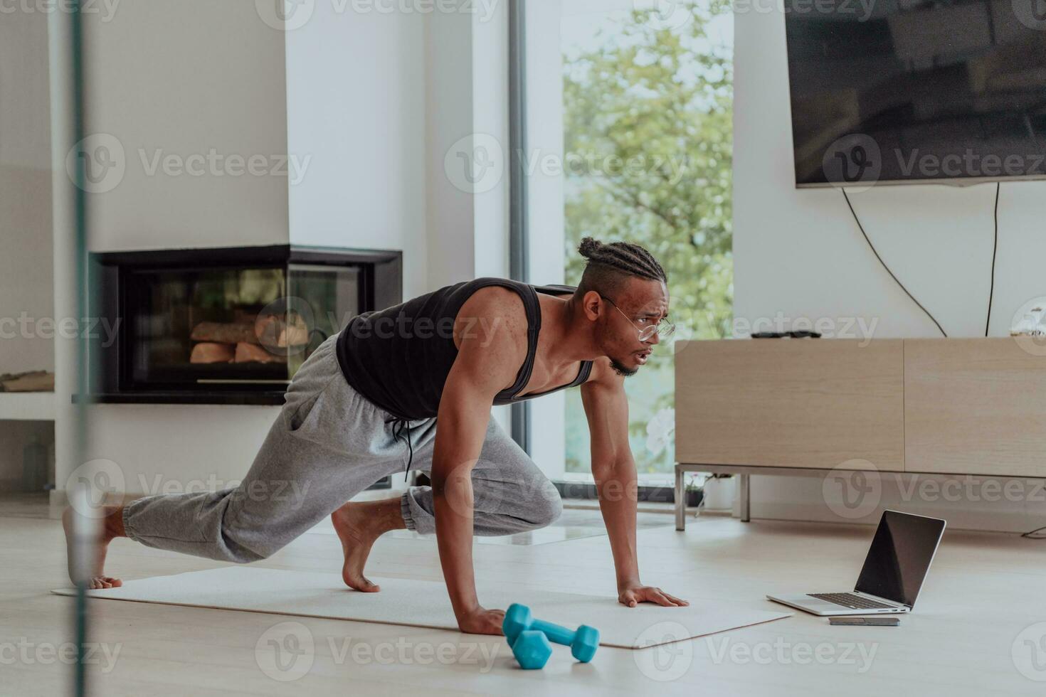 Training At Home. Sporty man doing training while watching online tutorial on laptop, exercising in living room, free space photo