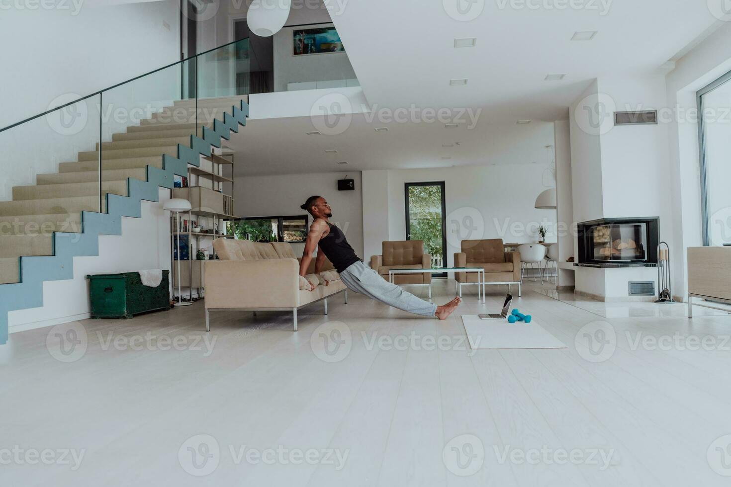 Training At Home. Sporty man doing training while watching online tutorial on laptop, exercising in living room, free space photo