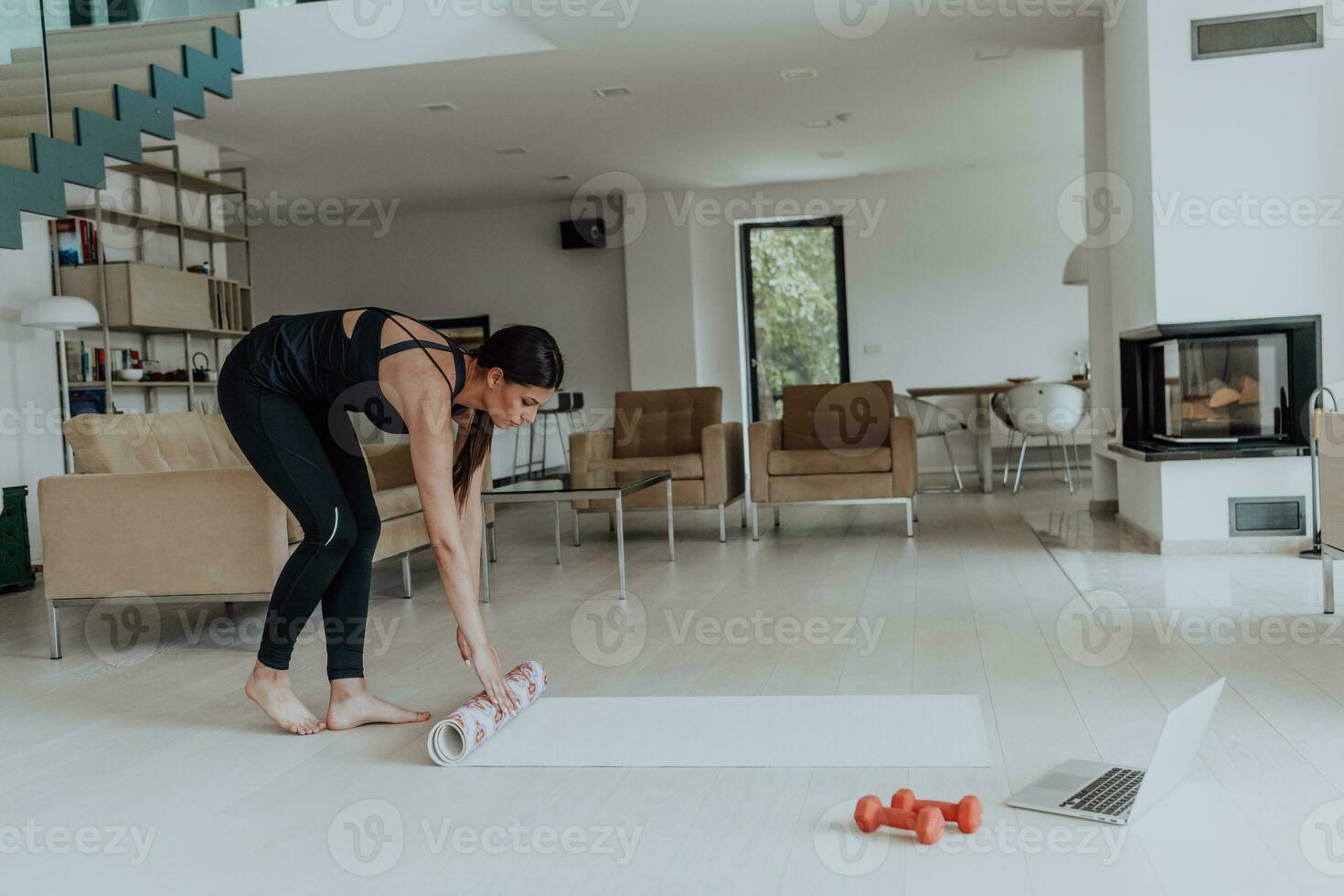 un joven mujer en Deportes ropa preparando Deportes equipo para en línea formación en su vivo habitación foto