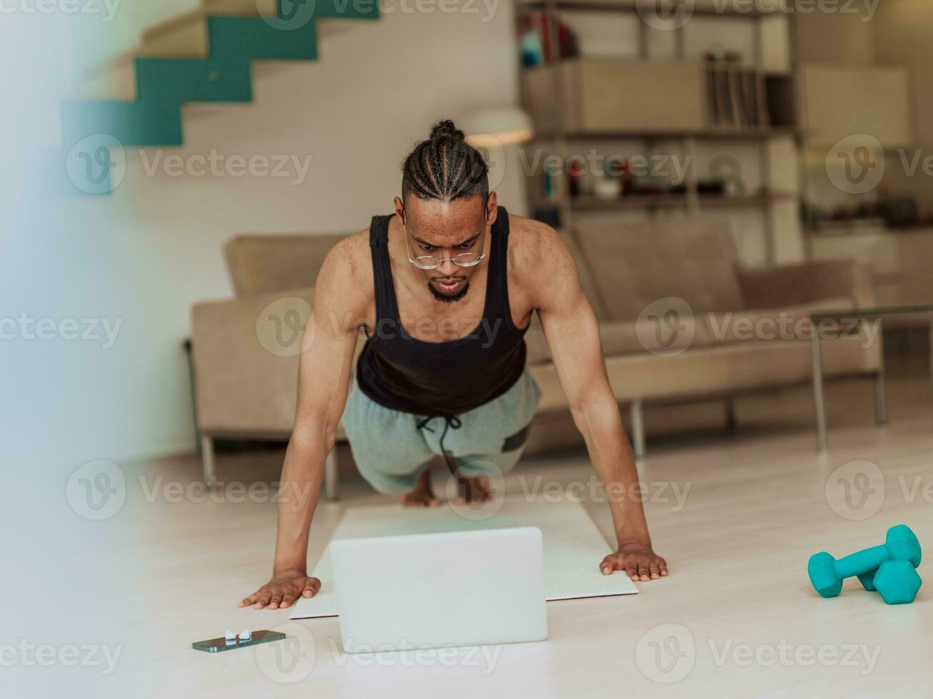 joven africano americano hombre trabajando Lagartijas en el vivo habitación mientras acecho en línea formación en ordenador portátil foto