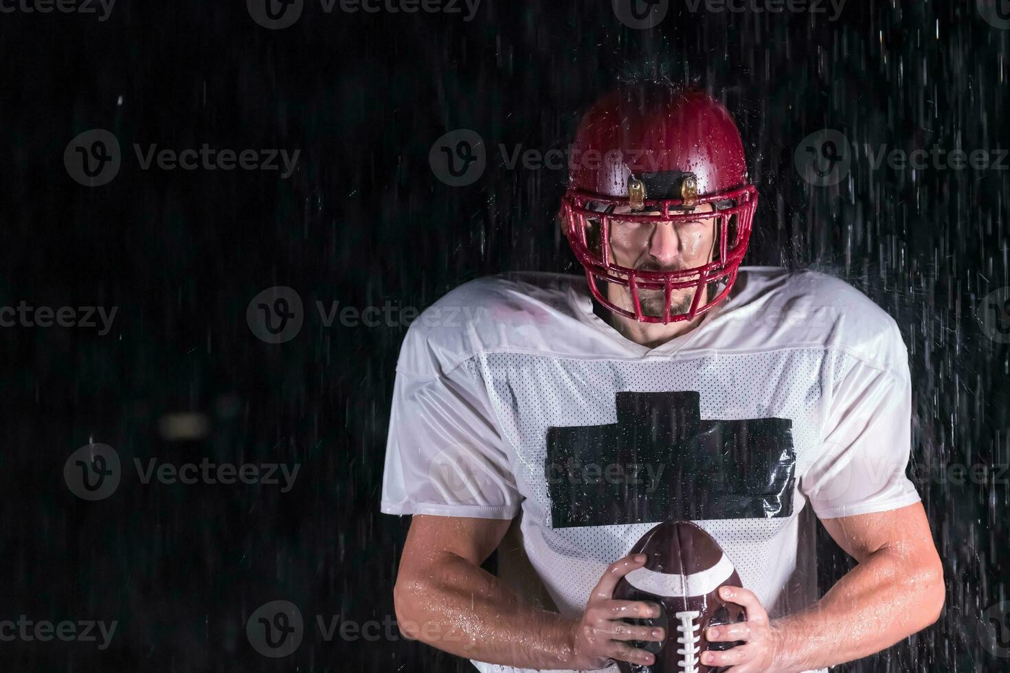 American Football Field Lonely Athlete Warrior Standing on a Field Holds his Helmet and Ready to Play. Player Preparing to Run, Attack and Score Touchdown. Rainy Night with Dramatic Fog, Blue Light photo