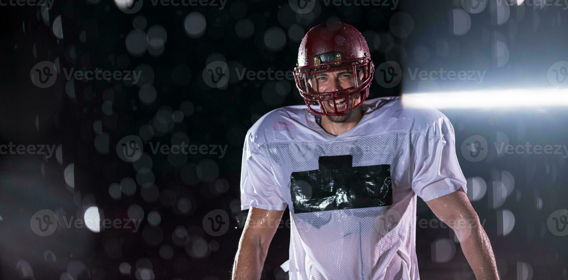 American Football Field Lonely Athlete Warrior Standing on a Field Holds his Helmet and Ready to Play. Player Preparing to Run, Attack and Score Touchdown. Rainy Night with Dramatic Fog, Blue Light photo