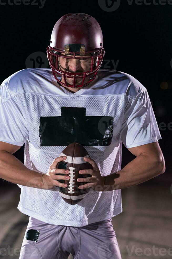 American Football Field Lonely Athlete Warrior Standing on a Field Holds his Helmet and Ready to Play. Player Preparing to Run, Attack and Score Touchdown. Rainy Night with Dramatic Fog, Blue Light photo