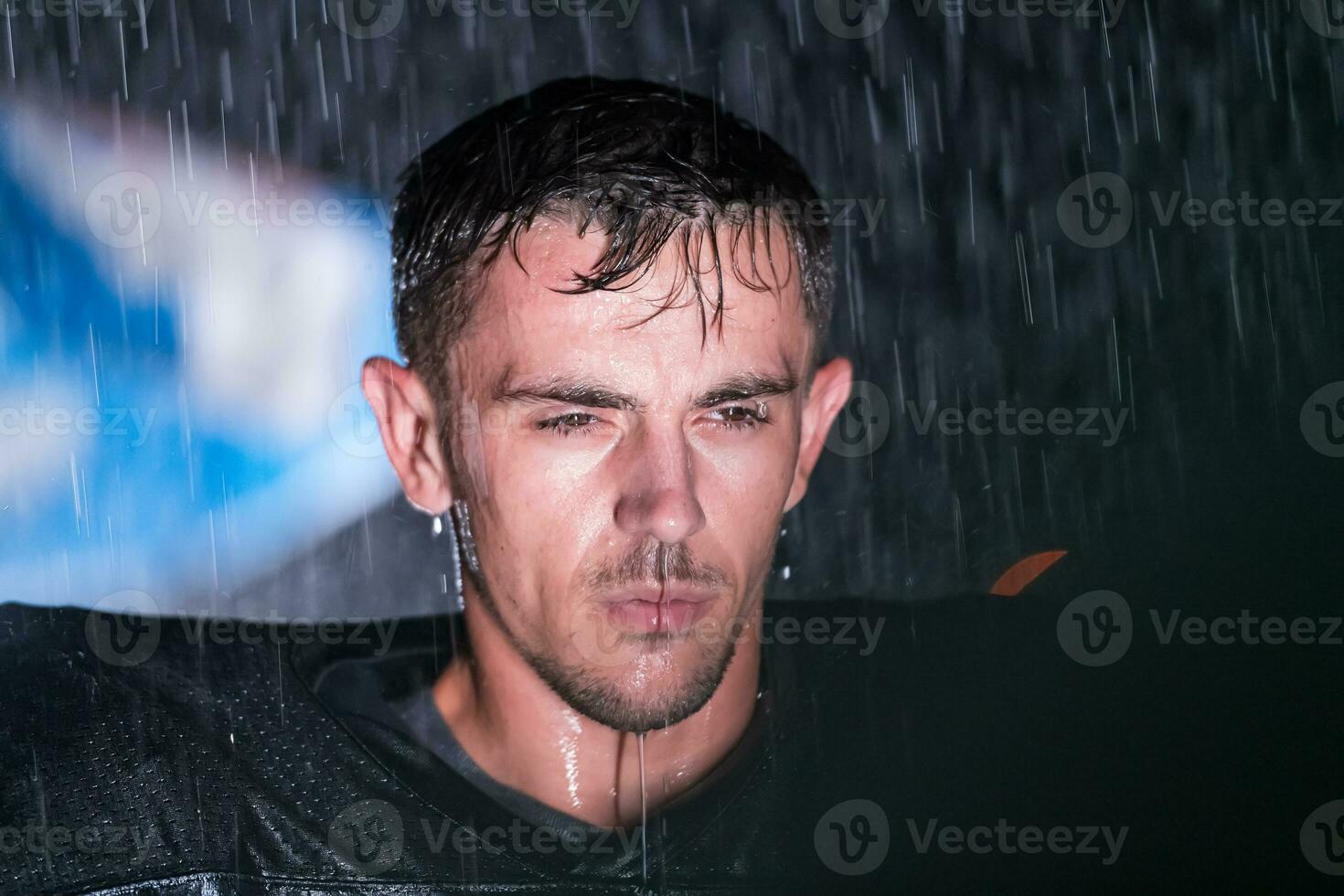 americano fútbol americano campo solitario atleta guerrero en pie en un campo sostiene su casco y Listo a jugar. jugador preparando a correr, ataque y Puntuación aterrizaje. lluvioso noche con dramático niebla, azul ligero foto