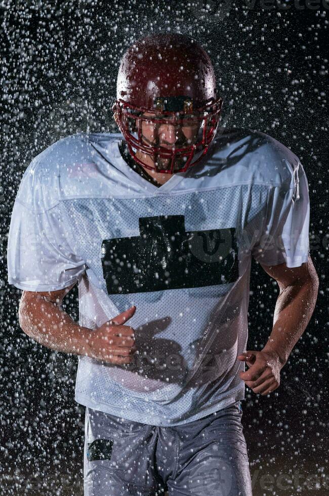 American Football Field Lonely Athlete Warrior Standing on a Field Holds his Helmet and Ready to Play. Player Preparing to Run, Attack and Score Touchdown. Rainy Night with Dramatic Fog, Blue Light photo