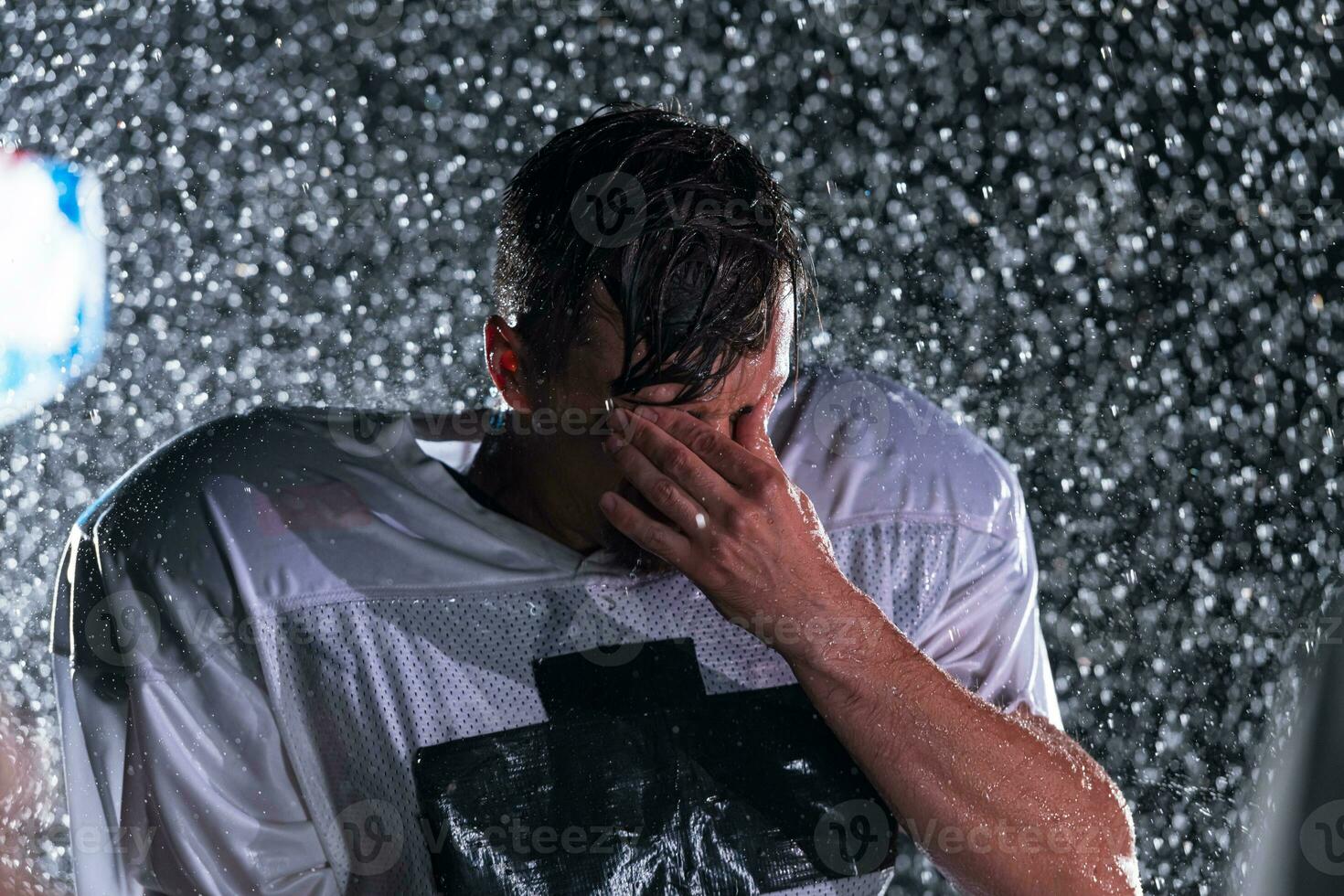 American Football Field Lonely Athlete Warrior Standing on a Field Holds his Helmet and Ready to Play. Player Preparing to Run, Attack and Score Touchdown. Rainy Night with Dramatic Fog, Blue Light photo