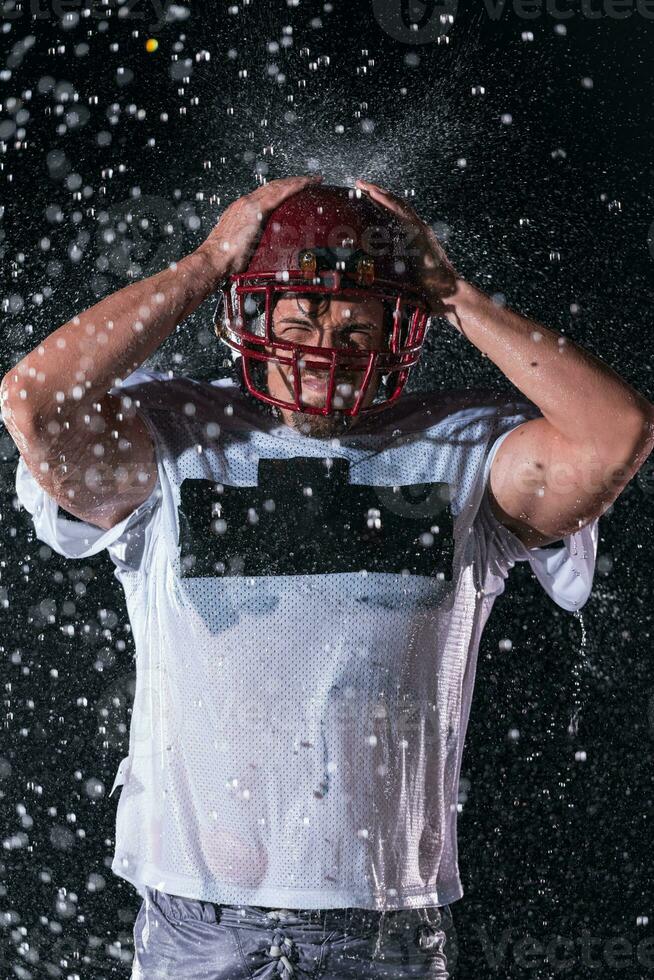 American Football Field Lonely Athlete Warrior Standing on a Field Holds his Helmet and Ready to Play. Player Preparing to Run, Attack and Score Touchdown. Rainy Night with Dramatic Fog, Blue Light photo